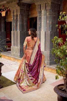 This shimmer organza lehenga choli adorned with zari weaving and delicate lace borders brings timeless elegance to every festive moment